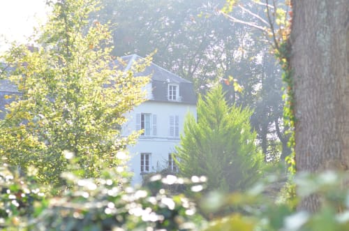 La Tour Blanche B&B nichée en forêt de Forest-Montiers, élégante demeure blanche entreperçue entre les arbres verdoyants et les fleurs