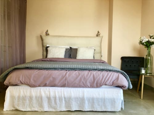 Elegantly styled bedroom at Villas Marincelu with layered bedding, cream headboard, and side table with flowers in Porto