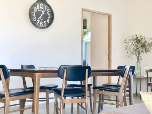 Modern dining area at Casa Felice villa in Porto Pollo with wooden table, navy chairs, and wall clock