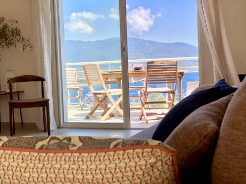 Casa Felice villa living room with sea view, wooden loungers on terrace overlooking Porto Pollo, Corsica mountains