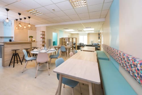 Espace repas et séjour moderne du B&B Un Air De Famille à Vittel avec tables en bois, chaises colorées, suspensions