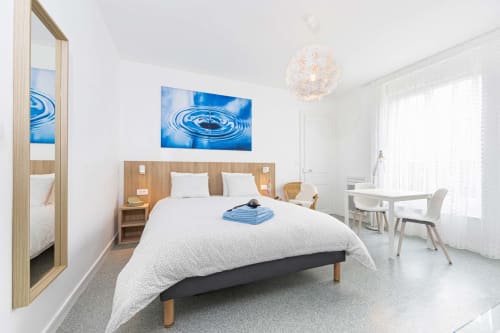 Chambre moderne de la maison d'hôtes Un Air De Famille à Vittel avec lit blanc, tête de lit en bois, œuvre d'art aquatique bleue et jardin