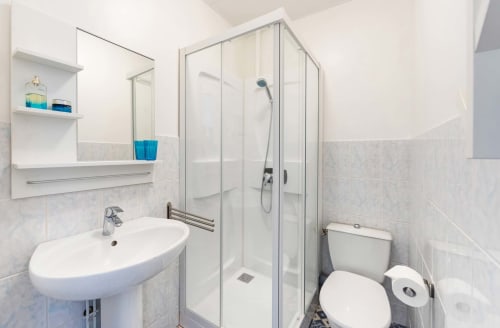 Salle de bain moderne avec lavabo sur piédestal blanc, douche vitrée et toilettes à la Côté Châtillon d'Un Air De Famille