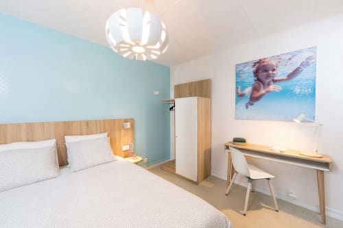 Chambre moderne du gîte Un Air De Famille à Vittel avec mur d'accent turquoise, lit en bois, bureau et enfant qui nage