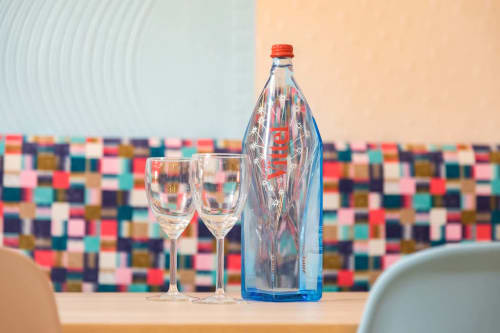 Deux verres de vin à côté d'une bouteille d'eau au bouchon rouge chez Un Air De Famille à Vittel