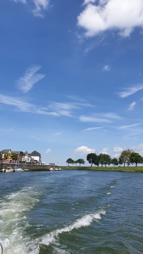 Vue sur le front de mer de Saint-Valery-sur-Somme avec plage, vagues, bateaux amarrés et charmants bâtiments riverside sous ciel bleu