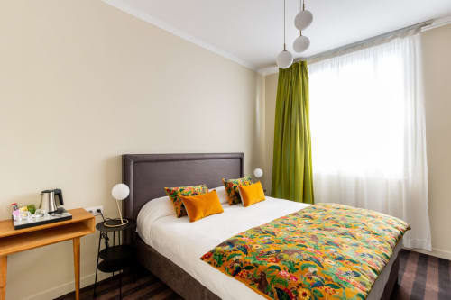 Modern studio bedroom at Hotel Residence Europe & Spa in Clichy with colorful patterned bedding, green curtains, pendant
