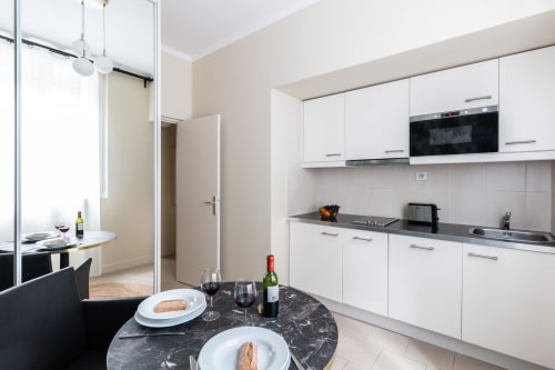 Studio apartment at Hotel Residence Europe & Spa featuring modern white kitchen, dining table with wine and bread, and living