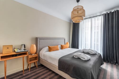 Modern hotel bedroom at Hotel Residence Europe & Spa in Clichy with king bed, wooden desk, woven pendant light, and