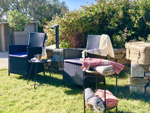 Outdoor seating area at Villas Marincelu villa with wicker chairs, side table, and colorful blankets on grass near stone