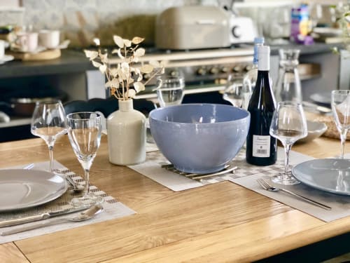 Elegant dining table setup at Villa Marincelu with wine glasses, plates, and blue bowl overlooking kitchen at sea view