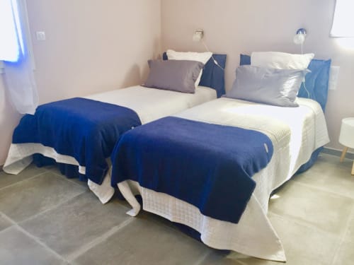 Twin beds with white sheets, blue blankets and gray pillows in a bright bedroom at Villas Marincelu villa in Corsica