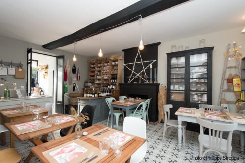 Salle à manger aux Filles du Bord de Mer, Port-en-Bessin avec tables en bois, luminaires suspendus et décoration côtière.