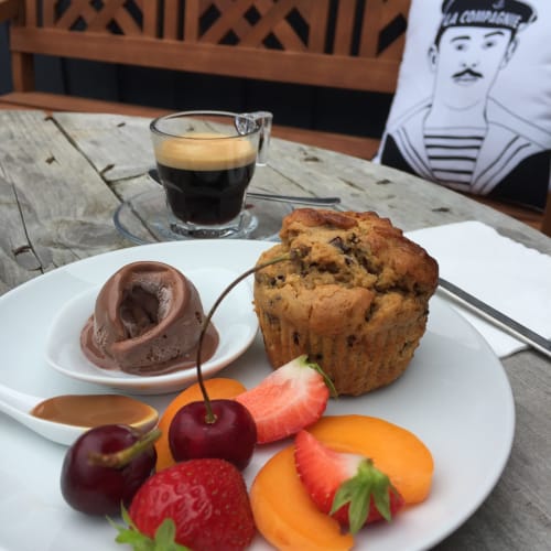 Assiette de dessert élégante aux Filles du Bord de Mer : mousse au chocolat, muffin, baies fraîches et fruits avec espresso.