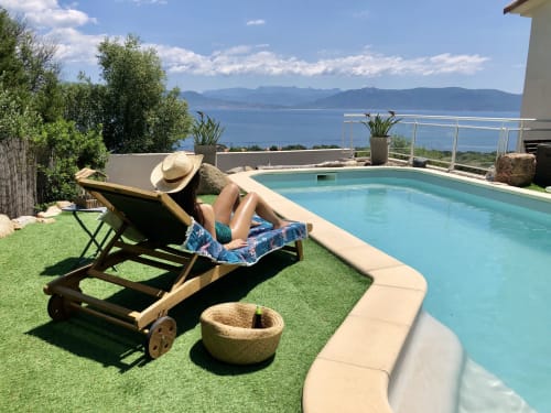 Guest relaxing in lounge chair by heated pool at Casa Felice villa, Porto Pollo, Corsica with sea views