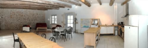 Area comune del Domaine de Lamartine a Pont-Saint-Esprit con tavoli da pranzo, cucina e travi in legno rustico