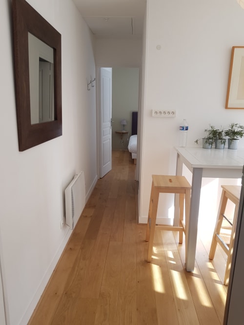 Lumineux couloir des Cabines à Houlgate avec parquet, murs blancs et cuisine avec bar