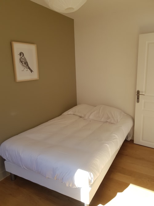 Chambre aux Cabines à Houlgate avec lit blanc, murs olive, œuvres d'art ornithologiques et parquet