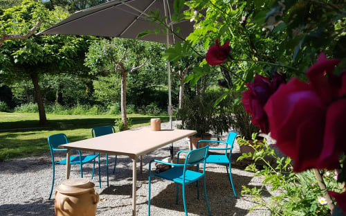 Buitenterras van Moulin Renaudiots in Autun met turquoise stoelen, eettafel, parasol en bloeiende rozen
