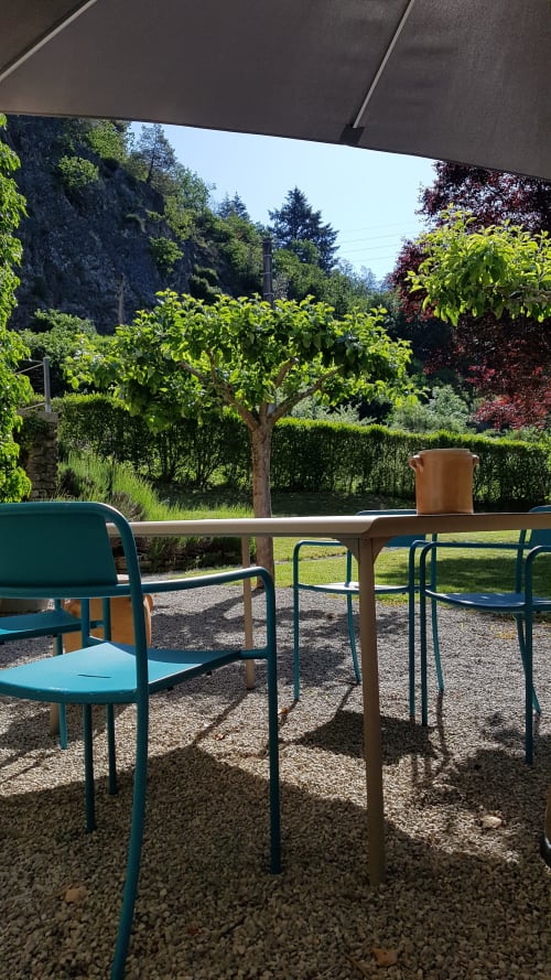 Schaduwrijk terras met zithoek in Moulin Renaudiots in Autun met turquoise stoelen, tafel en weelderige groene tuinen