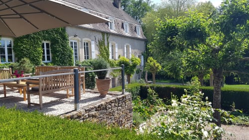 Tuinterras van Moulin Renaudiots in Autun met houten zitplaatsen, met klimop begroeide stenen gebouw en verzorgde landschapsarchitectuur