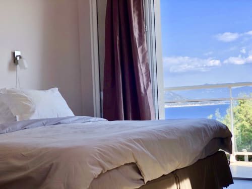 Bedroom with sea view at Casa Serena villa in Porto Pollo, Corsica, featuring bed, balcony, and Mediterranean coastline