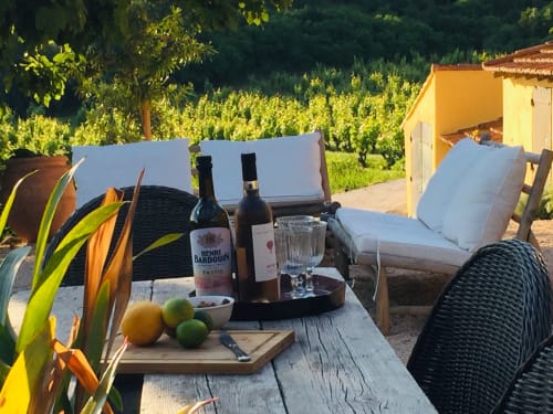Saint Martin B&B outdoor terrace in Ollioules with wine bottles, lounge chairs, and vineyard views at sunset