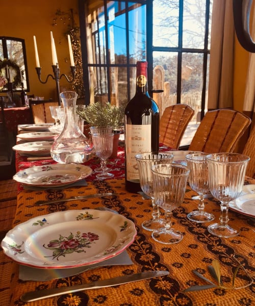 Elegant dining room at Saint Martin B&B in Ollioules with floral plates, wine bottle, and scenic mountain views
