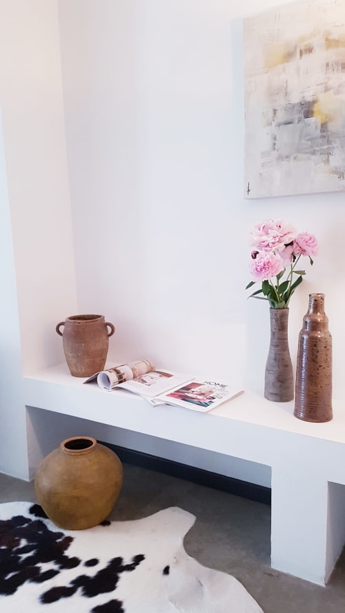 Moderne witte console met aardewerk, roze pioenrozen, tijdschriften en abstract kunstwerk in Hotel Moulin Renaudiots in Autun, Frankrijk