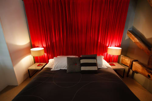 Modern bedroom at Moulin Renaudiots hotel in Autun with dramatic red curtains, ambient lighting, and contemporary furnishings