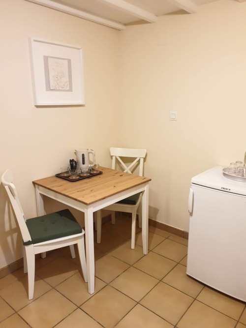 Small dining table with white chairs and wooden top in Cérise room at Villa Thébaïde, Laudun L'Ardoise, with coffee