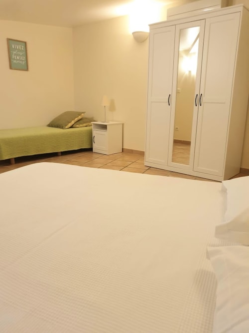 Spacious bedroom at Villa Thébaïde with white wardrobe, green bed, and tiled flooring in Laudun L'Ardoise