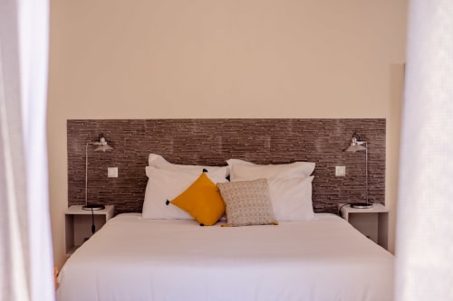 Chambre moderne au gîte Le Pignié à Lescure-d'Albigeois avec lit blanc, tête de lit texturée, coussin jaune et table de nuit