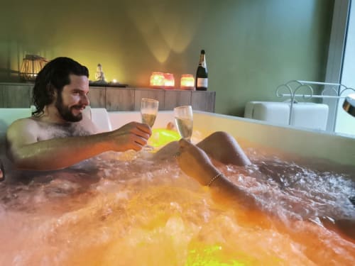 Homme se détendant dans un bain luxueux avec du champagne à La Cour d'Hortense, gîte à Sailly-Flibeaucourt, France