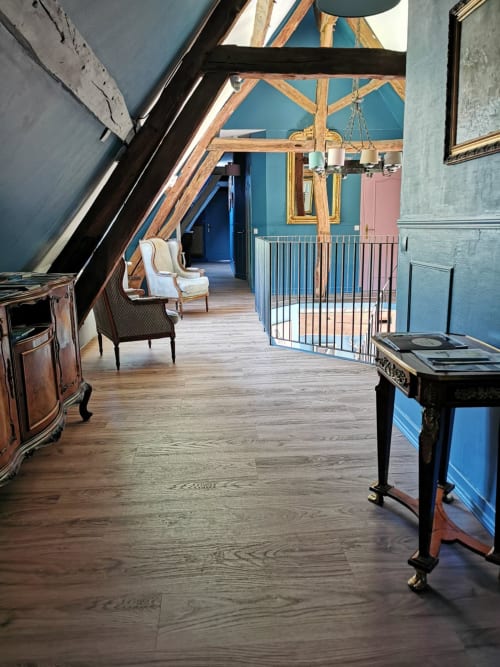 Couloir mansardé à La Cour d'Hortense avec plafond bleu, poutres apparentes, plancher en bois et mobilier d'époque.