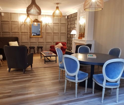 Le salon de l'hôtel Les Cabines à Houlgate avec table élégante, chaises bleues, cheminée et luminaires suspendus