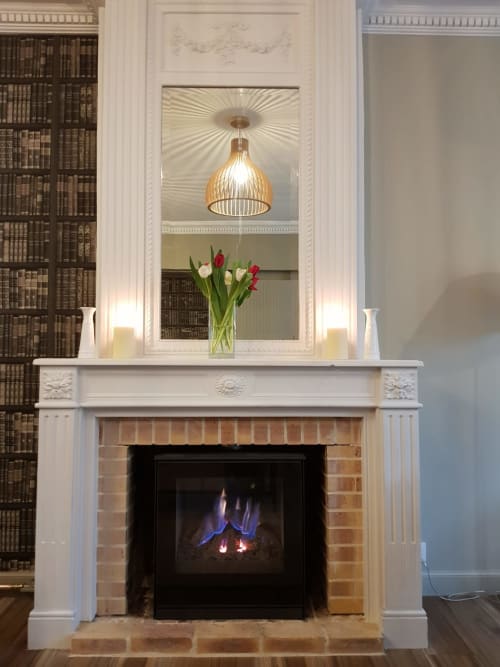 Cheminée élégante avec manteau blanc, miroir, luminaire suspendu et tulipes rouges et blanches à l'hôtel Les Cabines, Houlgate