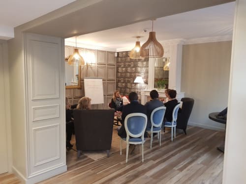 Salle de réunion à l'hôtel Les Cabines à Houlgate avec des clients autour d'une table et luminaires suspendus