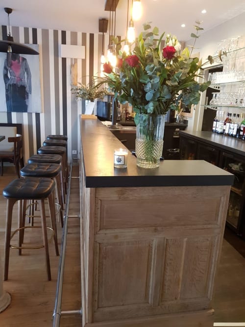 Le bar de l'hôtel Les Cabines à Houlgate avec comptoir en bois, roses rouges et décoration murale rayée