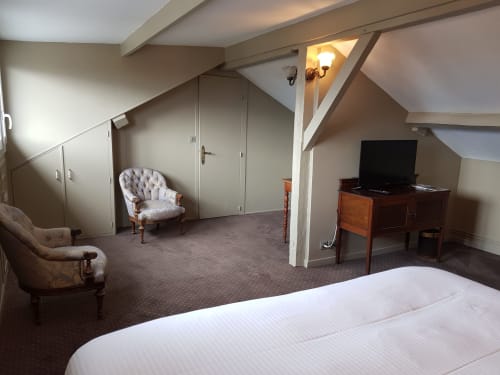 Suite Les Cabines avec vue mer à Houlgate : lit, espace détente, TV et bureau sous plafond mansardé