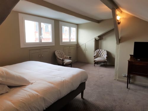 Spacieuse suite avec vue sur la mer à l'hôtel Les Cabines à Houlgate, comprenant un lit, des fauteuils capitonnés et de grandes fenêtres donnant sur l'océan.