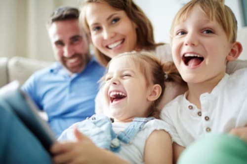 Happy family laughing together on couch at Hotel Residence Europe & Spa in Clichy