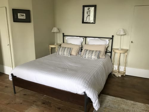 Chambre double beige à L'affable B&B aux Cammazes avec lit en fer forgé noir, draps blancs, lampes de chevet et vue sur le jardin