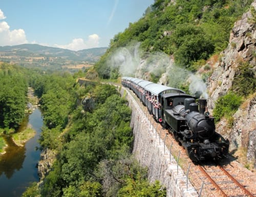 Train à vapeur historique circulant sur les voies pittoresques en falaise au-dessus de la vallée fluviale près de Chanos-Curson, France
