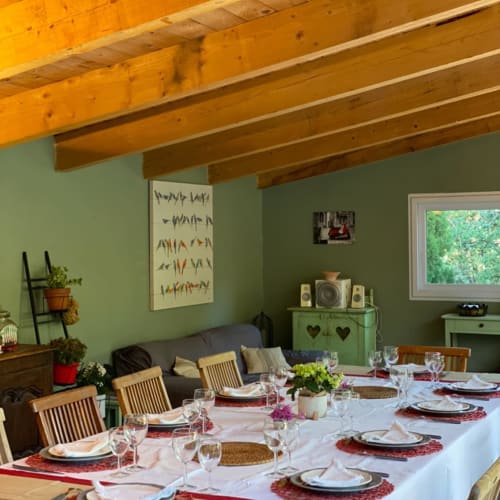 Dining room at Domaine Du Commandeur with wooden beams, green walls, and set table for guests