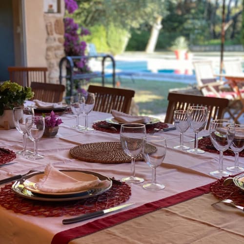 Elegant outdoor dining setup at Domaine Du Commandeur with pink tablecloth, burgundy accents, wine glasses, and pool view