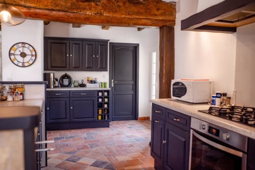 Modern cottage kitchen at Le Pignié gîte in Lescure-d'Albigeois with dark navy cabinets, terracotta tile flooring, and