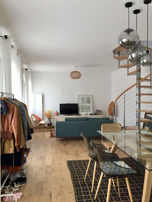 Loft moderne à La Conciergerie de Nathalie à Dinan avec canapé vert, escalier en bois et luminaires suspendus
