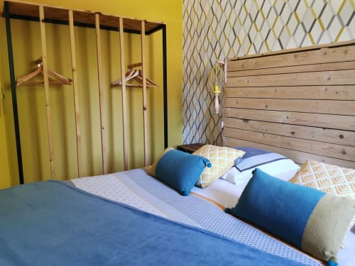 Chambre moderne du gîte La Cour d'Hortense à Sailly-Flibeaucourt avec literie bleue, tête de lit en bois et accent jaune