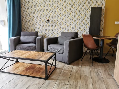 Élégant salon au gîte La Cour d'Hortense avec fauteuils gris, tables basses en bois et papier peint géométrique
